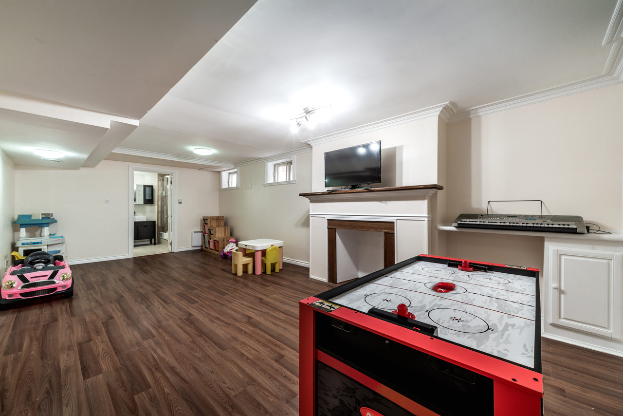 A Basement area remodeled to function as a Recreational room, with children's toys and a mini table and chair set, an electric keyboard, and an air hockey game table