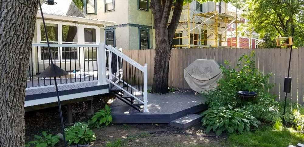 A backyard deck; a tree unbothered in the middle of the first level deck