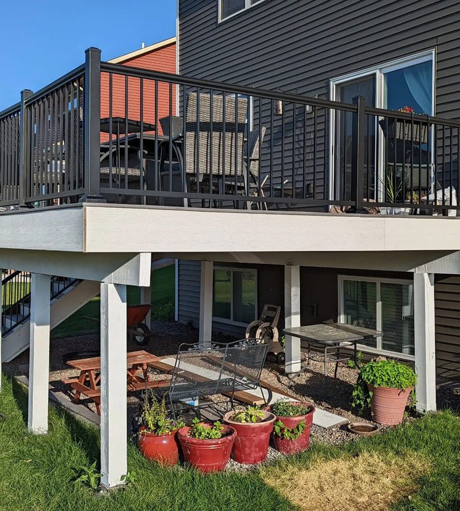 A raised open deck with an additional working area below, surrounded by pots of plants