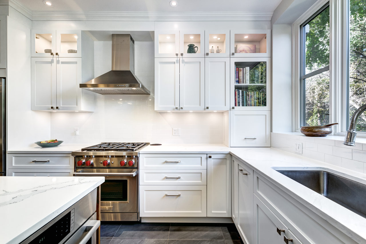 Kitchen Interior with stove range and oven, an exhaust hood, white cabinets with recessed lights